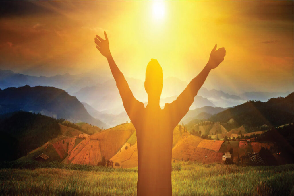 guy worshiping in a field with a sunset rise